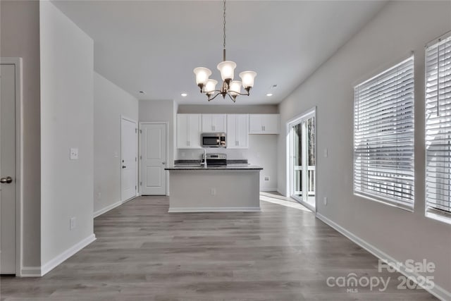 kitchen with dark countertops, baseboards, stainless steel microwave, and white cabinets