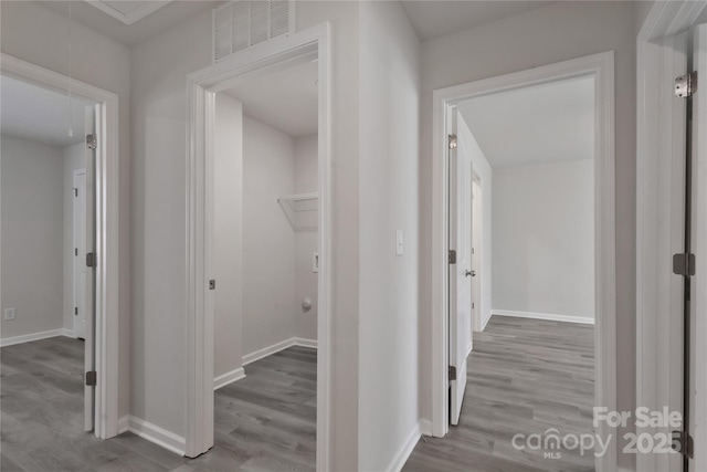 hall featuring attic access, visible vents, baseboards, and wood finished floors