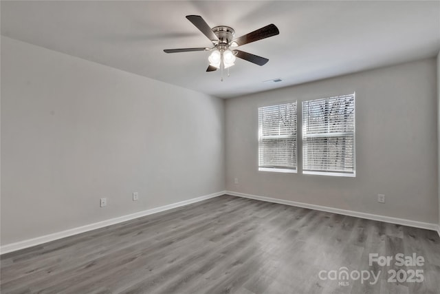 empty room with baseboards, visible vents, ceiling fan, and wood finished floors