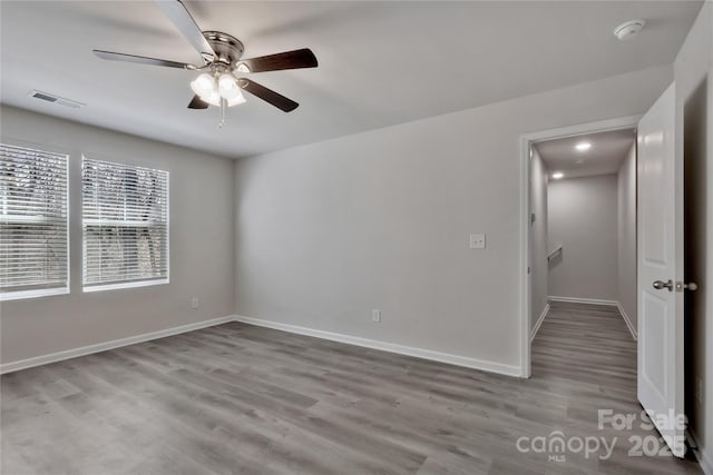 unfurnished room featuring ceiling fan, wood finished floors, visible vents, and baseboards