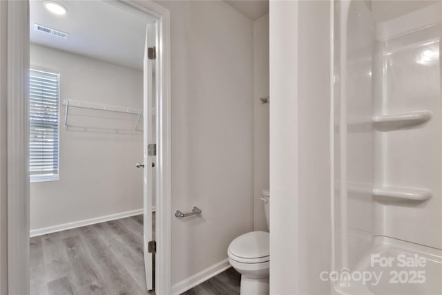 full bathroom featuring toilet, wood finished floors, visible vents, baseboards, and a shower