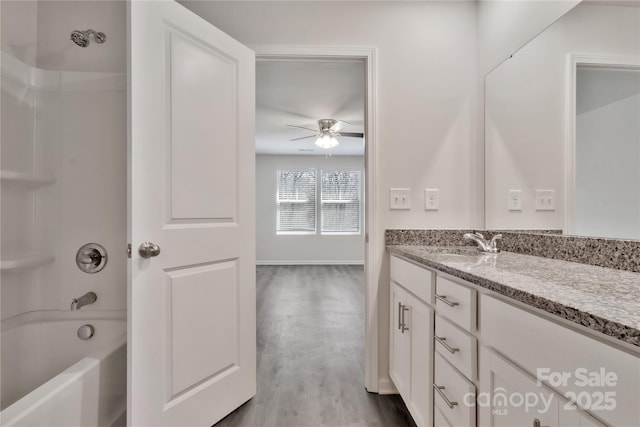 full bathroom featuring baseboards, ceiling fan, vanity, wood finished floors, and shower / bathtub combination