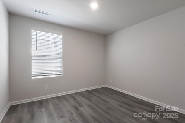 spare room featuring visible vents, baseboards, and wood finished floors