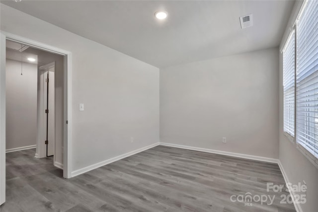 unfurnished room with recessed lighting, wood finished floors, visible vents, baseboards, and attic access