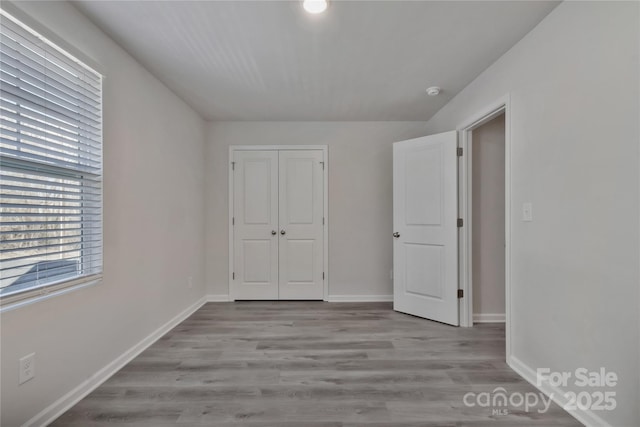 unfurnished bedroom featuring a closet, baseboards, and wood finished floors