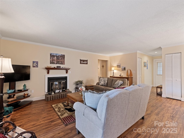 living area featuring a textured ceiling, ornamental molding, wood finished floors, and a glass covered fireplace