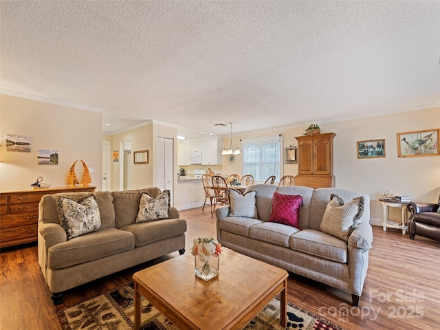 living room featuring a textured ceiling, ornamental molding, wood finished floors, and baseboards