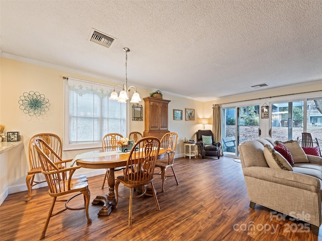 dining room featuring an inviting chandelier, visible vents, dark wood finished floors, and crown molding