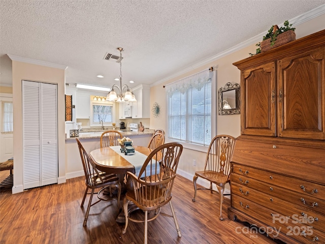 dining area with dark wood-style floors, baseboards, ornamental molding, and a chandelier