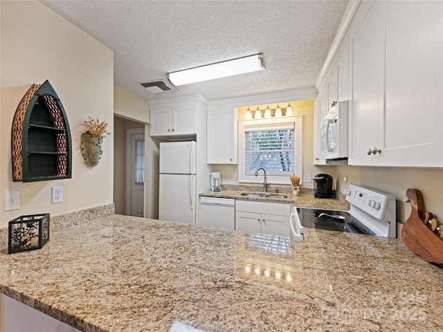 kitchen with white appliances, a sink, light stone counters, and white cabinets