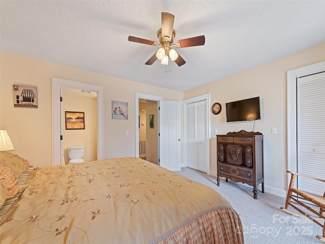 bedroom featuring baseboards, ceiling fan, a textured ceiling, carpet flooring, and two closets