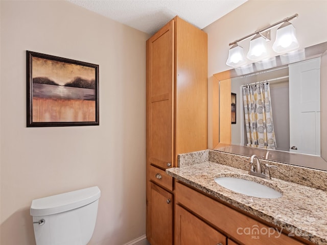 bathroom featuring a shower with curtain, vanity, toilet, and a textured ceiling