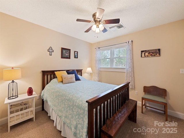 carpeted bedroom with ceiling fan, a textured ceiling, visible vents, and baseboards