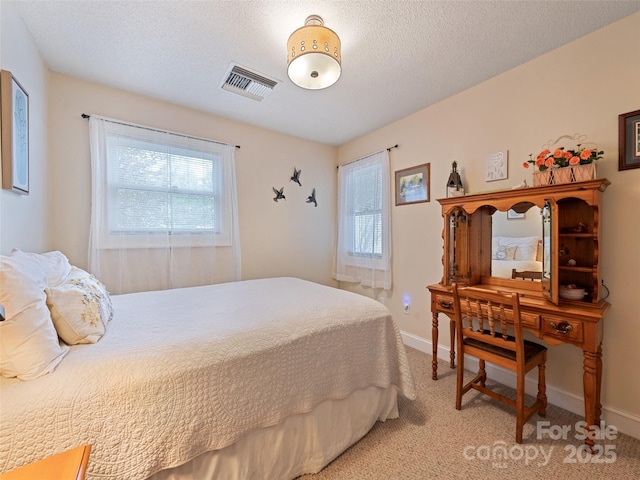 bedroom featuring baseboards, visible vents, light carpet, and a textured ceiling