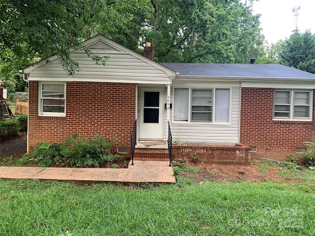 view of front of property featuring crawl space, brick siding, a chimney, and roof with shingles