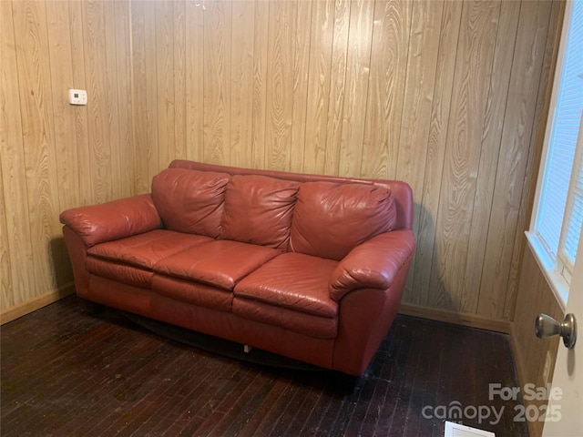 living room featuring wood walls, visible vents, baseboards, and hardwood / wood-style flooring