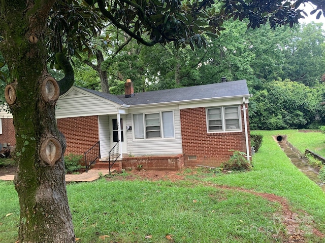 ranch-style home with a front yard, crawl space, brick siding, and a chimney