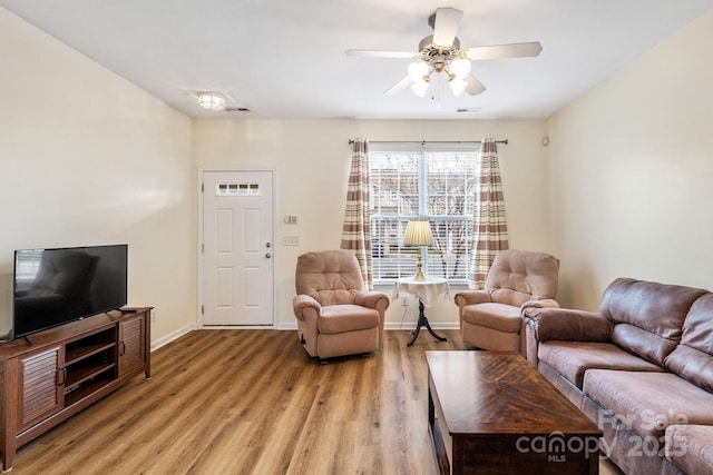 living area with light wood finished floors, ceiling fan, and baseboards