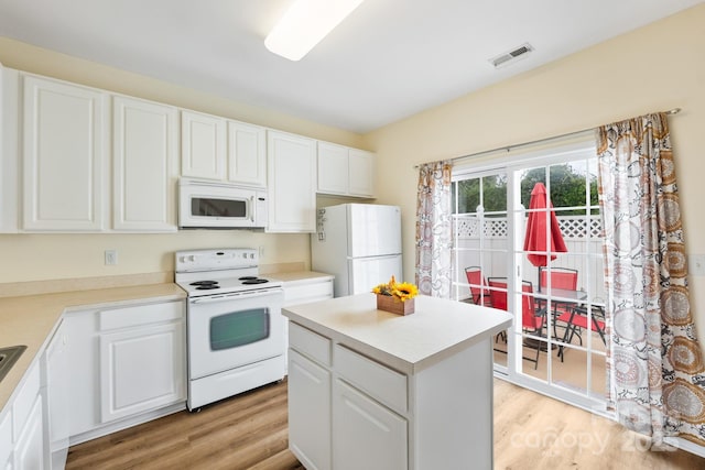 kitchen with white appliances, visible vents, and white cabinets