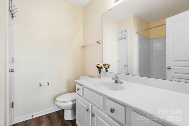 bathroom featuring baseboards, vanity, toilet, and wood finished floors