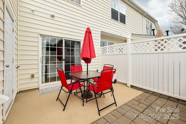 view of patio featuring outdoor dining area and fence