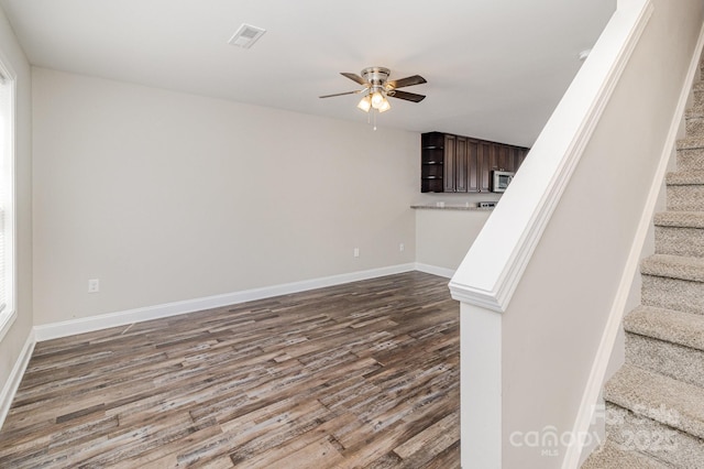 interior space featuring ceiling fan, stairway, dark wood finished floors, and baseboards