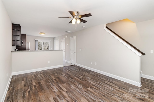 unfurnished living room with dark wood-style floors, ceiling fan, stairs, and baseboards