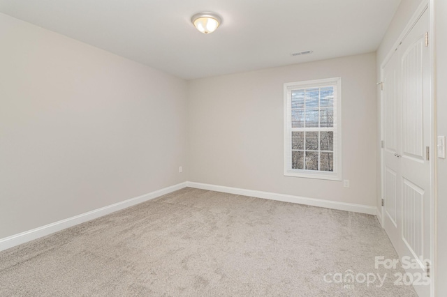 carpeted spare room featuring visible vents and baseboards