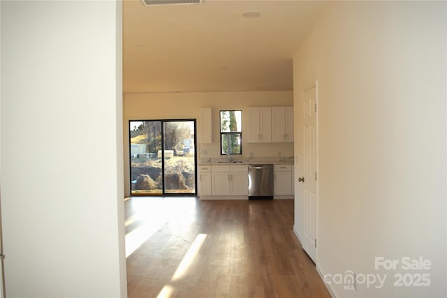 hallway with light wood-style floors, visible vents, and a sink