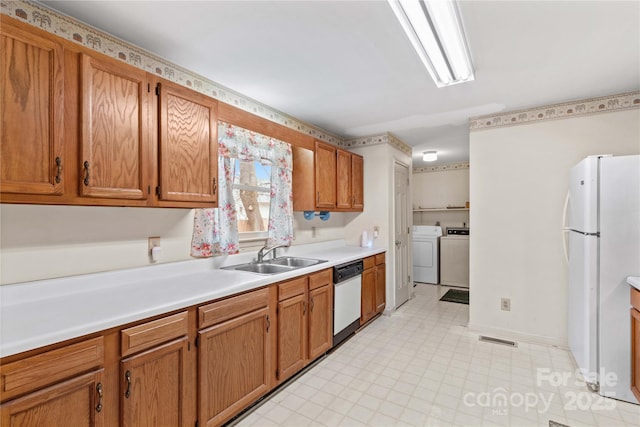 kitchen featuring visible vents, independent washer and dryer, a sink, white appliances, and light floors