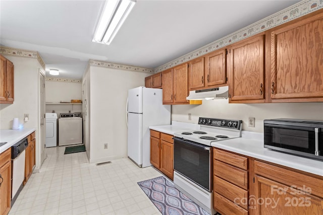 kitchen featuring under cabinet range hood, washer and dryer, white appliances, and light countertops