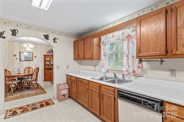 kitchen featuring wallpapered walls, light countertops, white dishwasher, arched walkways, and a sink