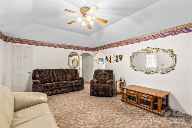 living area featuring ceiling fan, lofted ceiling, carpet flooring, arched walkways, and a raised ceiling