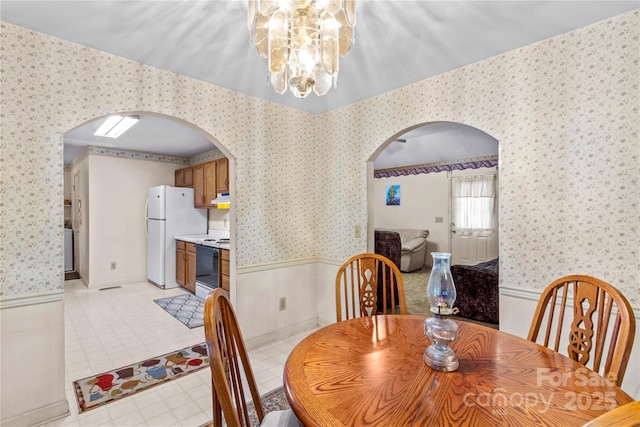 dining area with arched walkways and wallpapered walls