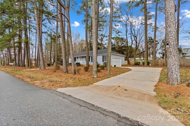 ranch-style house with concrete driveway, fence, and a garage