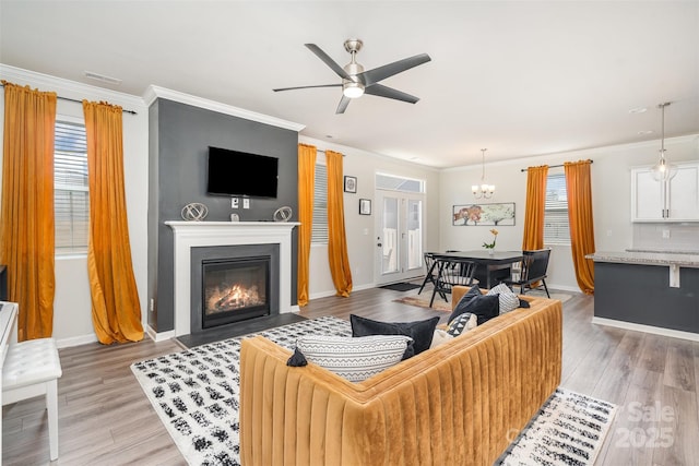 living room with crown molding, a fireplace with flush hearth, light wood-style floors, and baseboards