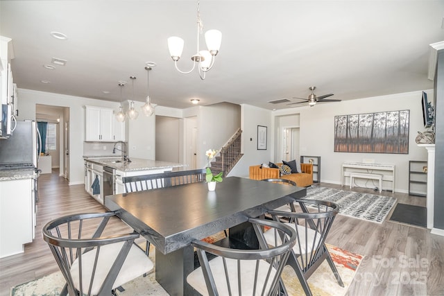 dining space with baseboards, ornamental molding, stairs, ceiling fan with notable chandelier, and light wood-type flooring