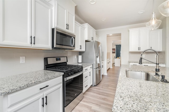 kitchen with ornamental molding, a sink, backsplash, stainless steel appliances, and white cabinets