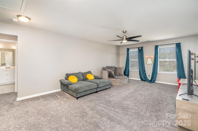 carpeted living area with attic access, a ceiling fan, and baseboards