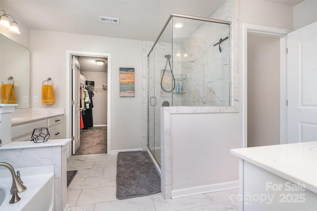 bathroom with visible vents, a spacious closet, marble finish floor, and a shower stall