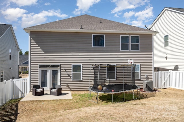 rear view of property with a yard, a fenced backyard, central AC, a trampoline, and a patio area