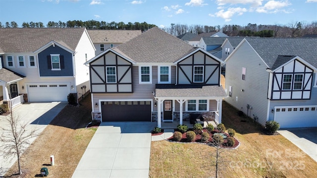 tudor home featuring a porch, concrete driveway, stone siding, and roof with shingles