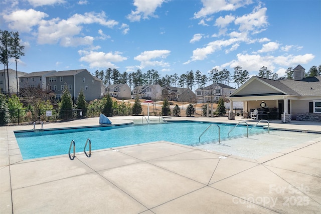 pool with a residential view, fence, and a patio area