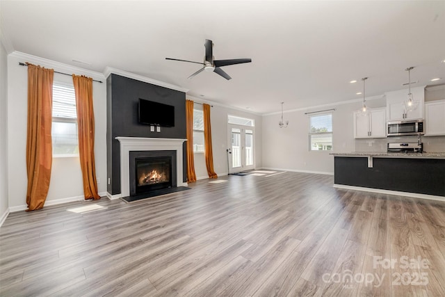 19113 Hawk Haven Ln, Charlotte, NC 28278 - unfurnished living room featuring ornamental molding, light wood-type flooring, a ceiling fan, a glass covered fireplace, and recessed lighting