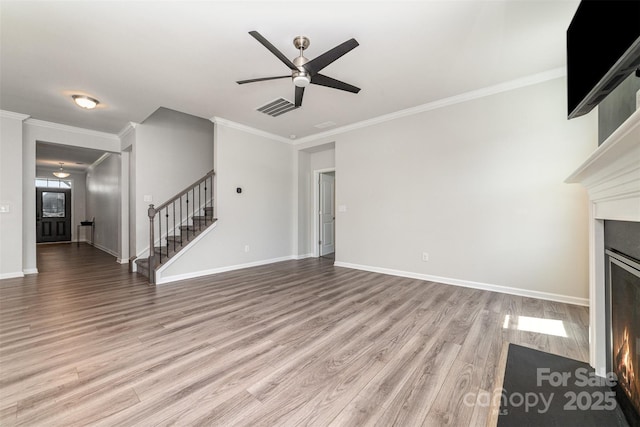 19113 Hawk Haven Ln, Charlotte, NC 28278 - unfurnished living room featuring a ceiling fan, stairway, a warm lit fireplace, light wood-style floors, and ornamental molding