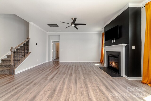19113 Hawk Haven Ln, Charlotte, NC 28278 - unfurnished living room featuring ceiling fan, light wood finished floors, a fireplace with flush hearth, stairs, and crown molding