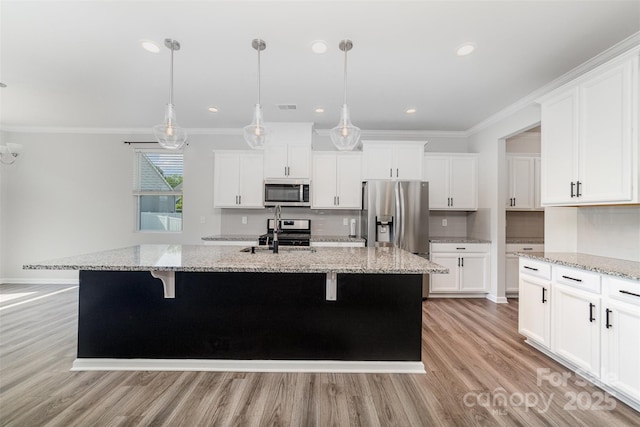 19113 Hawk Haven Ln, Charlotte, NC 28278 - kitchen with appliances with stainless steel finishes, crown molding, light wood finished floors, white cabinetry, and a center island with sink