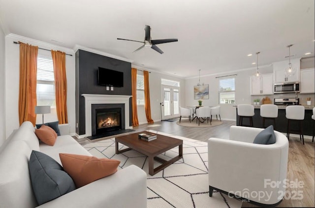 19113 Hawk Haven Ln, Charlotte, NC 28278 - living area featuring crown molding, light wood-style flooring, ceiling fan, recessed lighting, and a glass covered fireplace