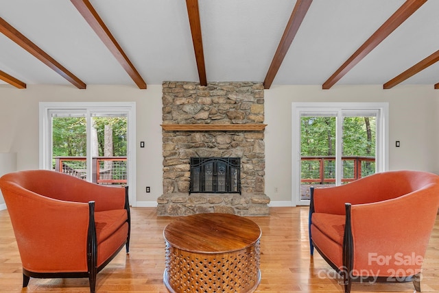 living area featuring light wood-style floors, a healthy amount of sunlight, and a stone fireplace