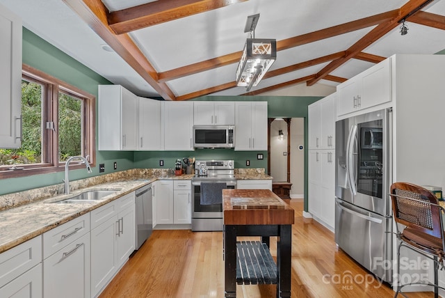 kitchen featuring stainless steel appliances, light stone counters, a sink, and white cabinetry